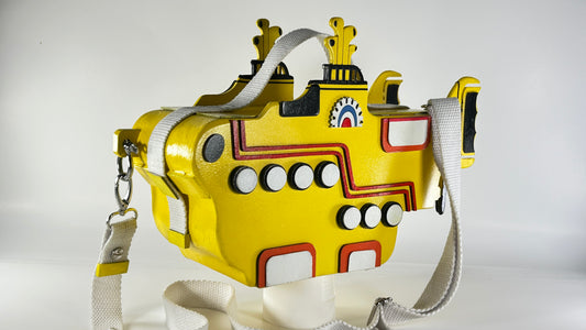 Yellow submarine-shaped bag with white shoulder and hand straps.